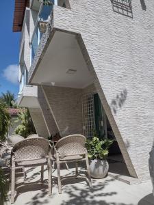 two chairs sitting on a patio in front of a building at Flat Beach Selma in Porto De Galinhas