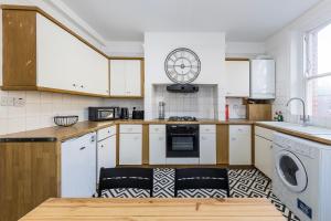 a kitchen with white cabinets and a washer and dryer at Indigo City Apartment in London