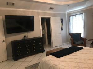a bedroom with a bed and a flat screen tv at Cheerful 4 bedroom home with pool and BBQ area with 5th bedroom option in Brownsville