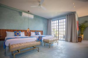 Turquoise Tulum Hotel في تولوم: غرفة نوم بسريرين ونافذة كبيرة