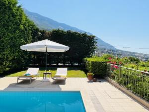 een zwembad met een parasol en twee stoelen en een tafel met een parasol bij Villa Marianna in Lourdhata