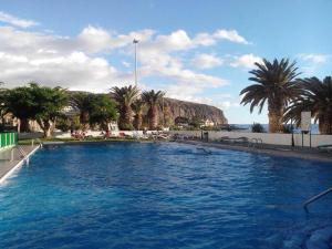 a person swimming in a large swimming pool with palm trees at Comodoro Los Cristianos 301A in Los Cristianos