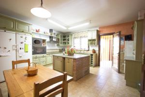 a large kitchen with green cabinets and a wooden table at Catalunya Casas Incredible secluded villa, just 11km from Beach! in La Selva del Camp