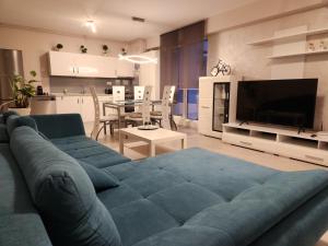 a living room with a blue couch and a kitchen at Airport Apartment Otopeni in Otopeni