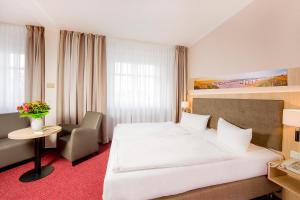 a bedroom with a large white bed and a chair at Garni Eden Hotels in Ahlbeck