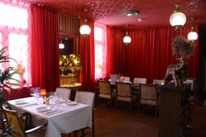 une salle à manger avec des tables, des chaises et des rideaux rouges dans l'établissement Örserumsbrunn Gestgifveri, à Gränna