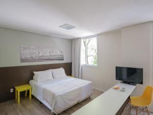 1 dormitorio con 1 cama, escritorio y TV en Açores Flat Design- Ao lado da Casa De Cultura Mário Quintana, en Porto Alegre