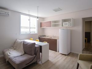 a kitchen with a couch and a table and a refrigerator at Açores Flat Design- Ao lado da Casa De Cultura Mário Quintana in Porto Alegre