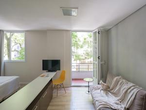a bedroom with a bed a desk and a couch at Açores Flat Design- Próximo ao Gasômetro e Cais Embarcadero in Porto Alegre