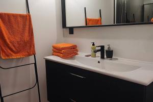 La salle de bains est pourvue d'un lavabo, d'une serviette orange et d'un miroir. dans l'établissement Appt d'artiste - 3 ch - Parking, à Rouen