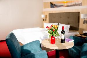 a hotel room with a table with a bottle of wine and flowers at Hotel Garni Sonne in Ahlbeck