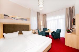 ein Hotelzimmer mit einem Bett und einem Tisch und Stühlen in der Unterkunft Hotel Garni Sonne in Ahlbeck