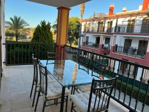 a glass table and chairs on the balcony of a building at Ayamonte Vista Esuri Golf - 12 min to Isla Canela in Huelva