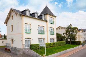 een groot wit huis met een zwart dak bij Hotel Garni Sonne in Ahlbeck