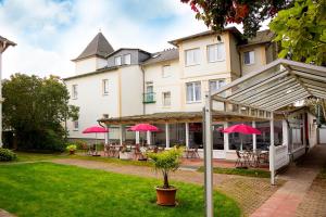 ein großes Gebäude mit Tischen und rosa Sonnenschirmen in der Unterkunft Hotel Garni Sonne in Ahlbeck