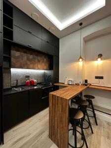 una cocina con armarios negros y una isla de madera con taburetes. en CC Atocha Apartments, en Madrid