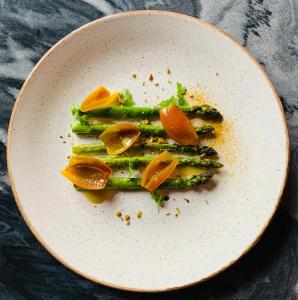 a white plate with asparagus and oranges on it at Gränna Strandhotell in Gränna