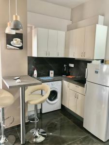 a kitchen with white cabinets and a washer and dryer at Apartment weekend by the sea in Loutraki