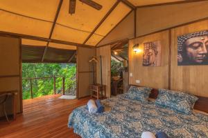Los Vivos Beachfront Experience في Pochote: غرفة نوم بسرير وشرفة