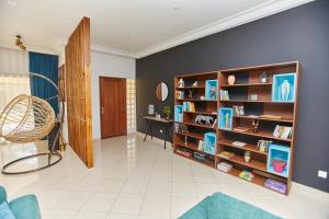 een woonkamer met een boekenplank met boeken bij Sompteuse villa avec piscine à 5 min de la plage in Pointe-Noire