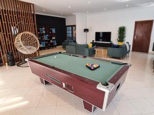 a living room with a pool table in the middle at Sompteuse villa avec piscine à 5 min de la plage in Pointe-Noire +23 photos