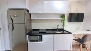 a kitchen with a stainless steel refrigerator and white cabinets at Canal do Anfitrião | Studios Jauperi in Sao Paulo
