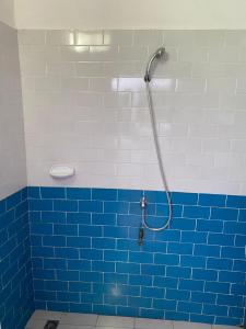 y baño con ducha de azulejos azules y cabezal de ducha. en PARADISE FB, en Cotonou