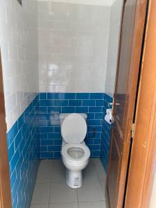 a blue tiled bathroom with a toilet in a stall at PARADISE FB in Cotonou +3 photos