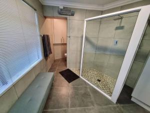une douche avec une porte vitrée dans une salle de bain dans l'établissement 1 on Fairway, à Bloemfontein 1 autre photo