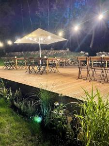a wooden deck with tables and an umbrella at night at Penzion Medové údolí in Čábuze