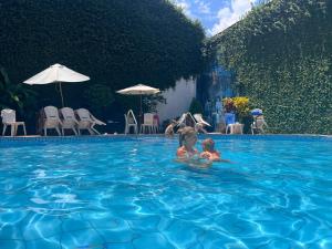 two children are swimming in a swimming pool at El Cauchero Hotel Iquitos in Iquitos