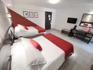 a hotel room with two beds and a desk at Ramada Plaza by Wyndham Leon in Le&oacute;n