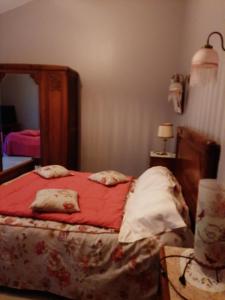 chambre d hotes في Saint-Laurent-de-la-Barrière: غرفة نوم مع سرير وملاءات حمراء ومرآة