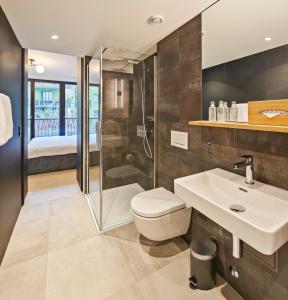 a bathroom with a shower and a toilet and a sink at Liv Suites in Luzern