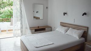 a white bedroom with a bed and a balcony at Ελαία Apartments in Edipsos
