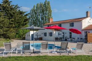 a group of chairs and umbrellas next to a pool at Gîtes Le Bois Berranger in Saint-Urbain