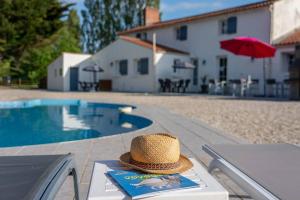 a straw hat sitting on a table next to a pool at Gîtes Le Bois Berranger in Saint-Urbain