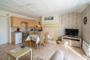 a kitchen and a living room with a table and a television at Gîtes Le Bois Berranger in Saint-Urbain
