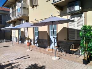 a patio with tables and umbrellas in front of a building at SMART HOME Certosa - Collegno in Collegno