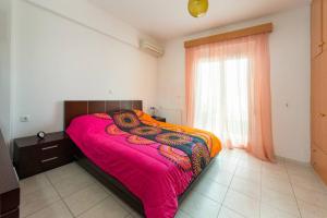 ein Schlafzimmer mit einem Bett mit einer rosa Decke und einem Fenster in der Unterkunft Garden House with sea view in Faliraki
