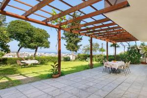 a patio with a table and chairs under a wooden pergola at Garden House with sea view in Faliraki