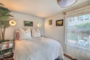 um quarto com uma cama com lençóis brancos e uma janela em Cute East Hampton Cottage with Patio - Walk to Beach em East Hampton
