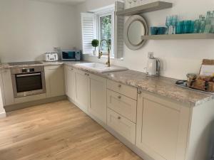 a kitchen with white cabinets and a counter top at The Bolt Hole Hythe panoramic coast and sea views in Kent