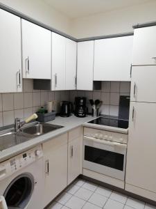 a kitchen with white cabinets and a sink and a dishwasher at Zum Feldstein in Themar