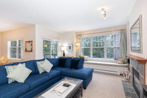a living room with a blue couch and windows at Deer Run by Whistler Premier in Whistler