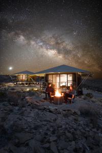 een groep van drie personen die 's nachts voor een tent zitten bij Camp Elena - Luxury Tents Minutes from Big Bend and Restaurants in Terlingua