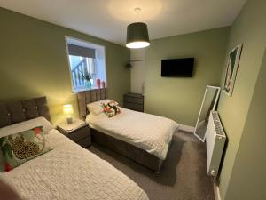 a small bedroom with two beds and a television at Regent Apartment - Two bedroomed Holiday Flat in Ilfracombe