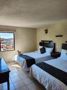 a hotel room with two beds and a window at Hotel 1988 Guanajuato in Guanajuato