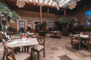 un restaurante con mesas, sillas y palmeras en El Edén Hotel Boutique en Pátzcuaro