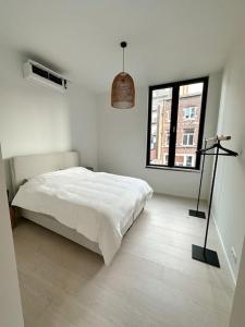 a white bedroom with a bed and a window at Appartement lumineux hyper centre in Liège